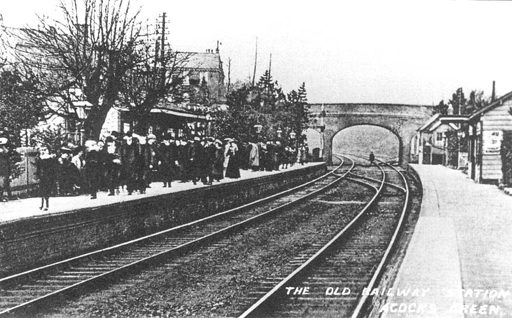 View of the down platform which is full of passengers waiting for a local passenger train to Snow Hill