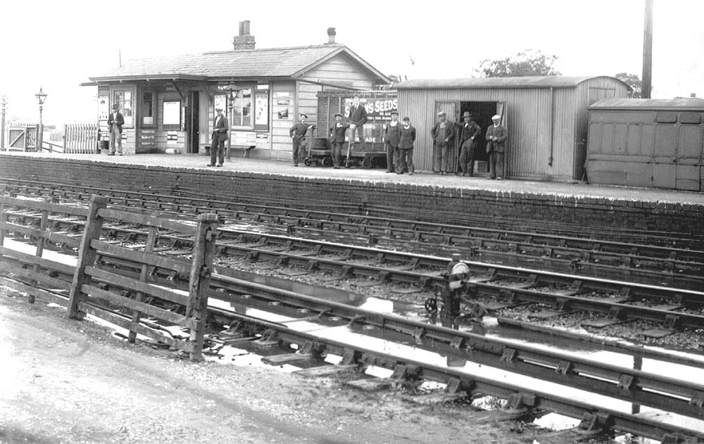 View of Fenny Compton station's up platform with ten non-uniformed railway workers posed for the camera