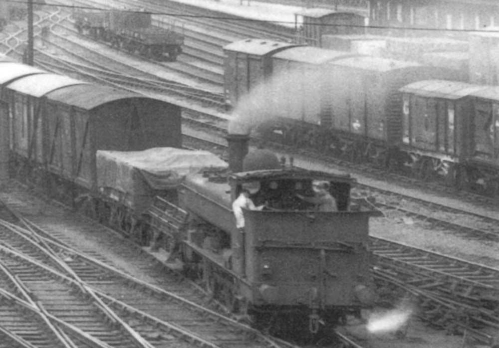 Close up showing an unidentified GWR half-cab 0-6-0PT marshalling a rake of box vans in the sidings