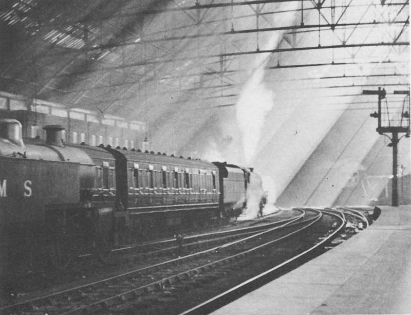 An unidentified LMS 4-6-0 Class 5 locomotive is seen blowing off steam at the East end of Platform 1 whilst at the head of a Birmingham to Euston express service