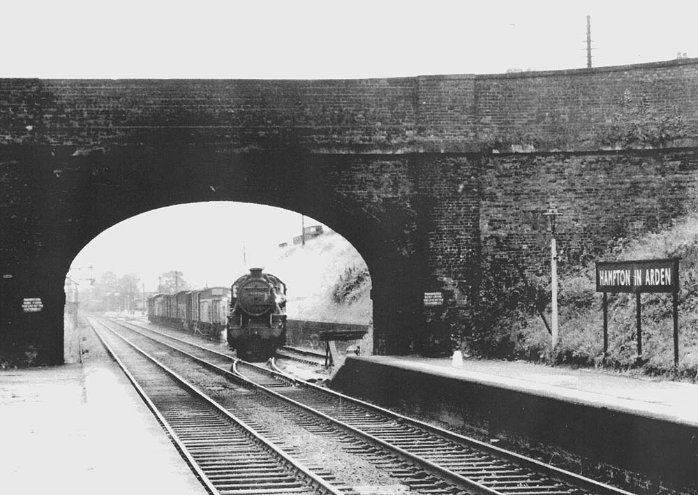 View of unidentified LMS 2-6-0 Stanier Mogul on an up local service freight train leaving the goods yard with the yard seen in the distance