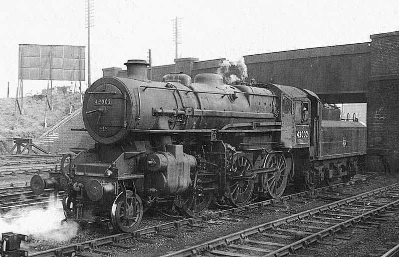 Ex-LMS 4MT 2-6-0 No 43002 pauses in the refuge siding by the bridge carrying the Leicester Road over the railway in June 1957