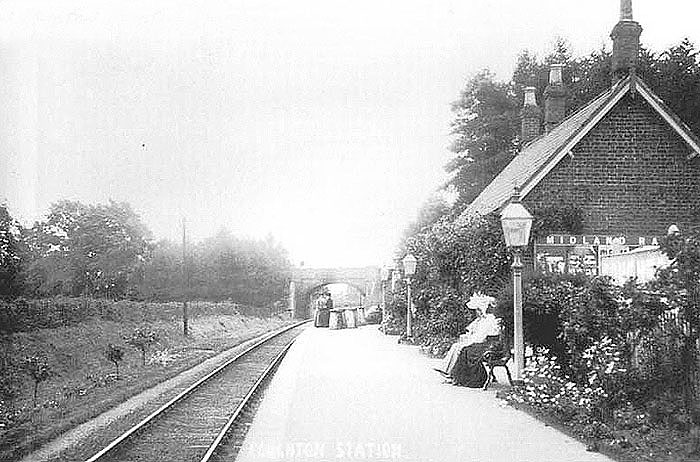 View of Coughton railway station looking towards Alcester with passengers and milk churns standing on the platform