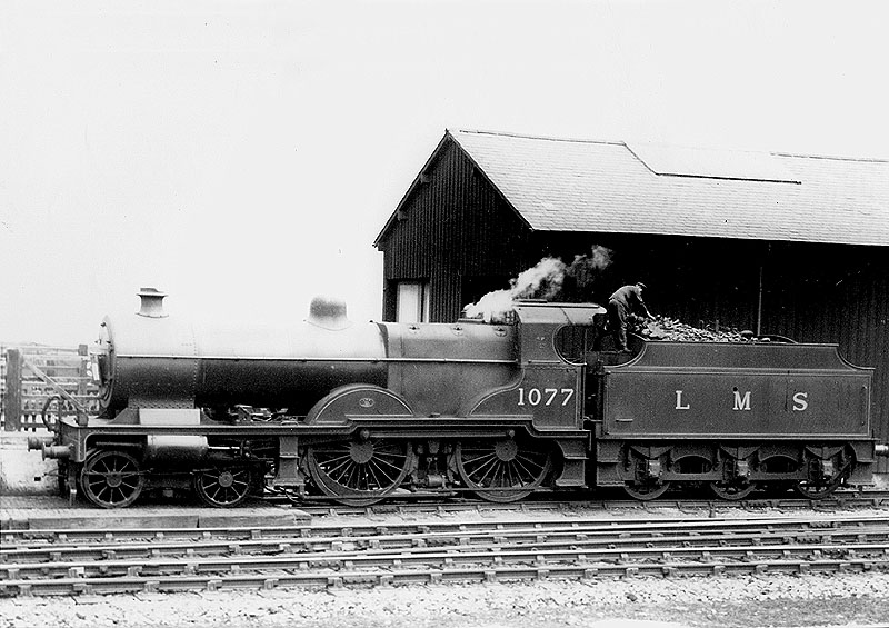LMS 4-4-0 "Compound" No 1077 stands light engine with the fireman working on the tender rearranging the coal to his satisfaction