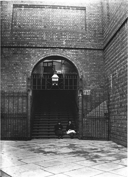 Two girls pose for SWA Newton's camera seated at the bottom of the staircase leading up to the station