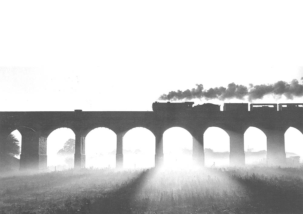 An LNER built K3 Class 2-6-0 locomotive is silhouetted against the morning sun whilst crossing the GCR viaduct just north of the 'Birdcage'