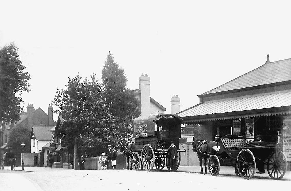 View of Acocks Green's station building housing the booking office and sited at road level with two horse-drawn vehicles outside of the building