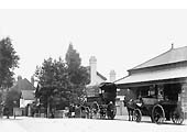 View of Acocks Green's station building housing the booking office and sited at road level with two horse-drawn vehicles outside of the building