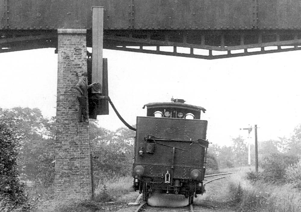 Close up showing the fireman of the 0-4-2T engine letting the water flow in to the bunker by controlling the wheel on the down pipe