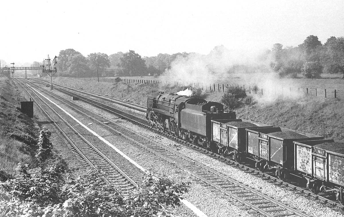 An unidentified British Railways 2-10-0 Standard Class 9F is approaching Bentley Heath crossing with an up coal train