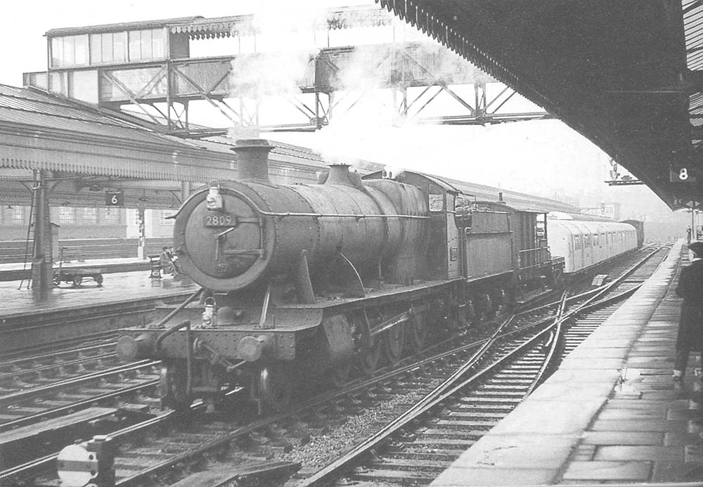 Ex-GWR 2-8-0 class 28xx No 2809 is seen passing through Snow Hill station's up through road whilst at the head of a train of underground rolling stock on 6th January 1958
