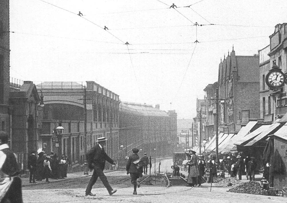 Close up showing passengers waiting for a tram on the left and on the right the tram stop being repaired at the junction of Snow Hill
