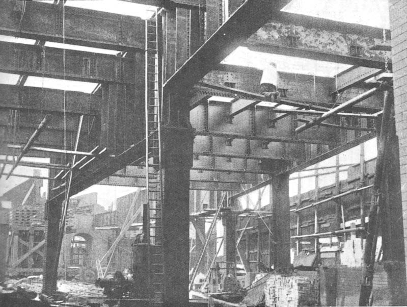 A picture from ground level showing the cross girders being fitted with steel supports for the third girder