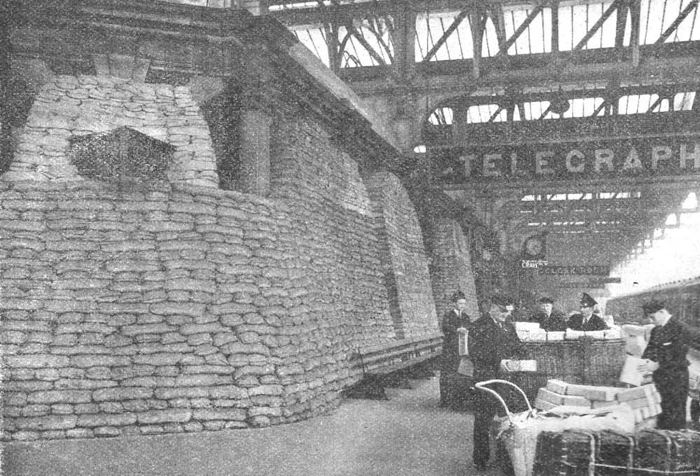 Porters at Birmingham Snow Hill continue sorting parcel traffic as normal outside the heavily sand-bagged telegraph offices on Platform No 7 in 1940
