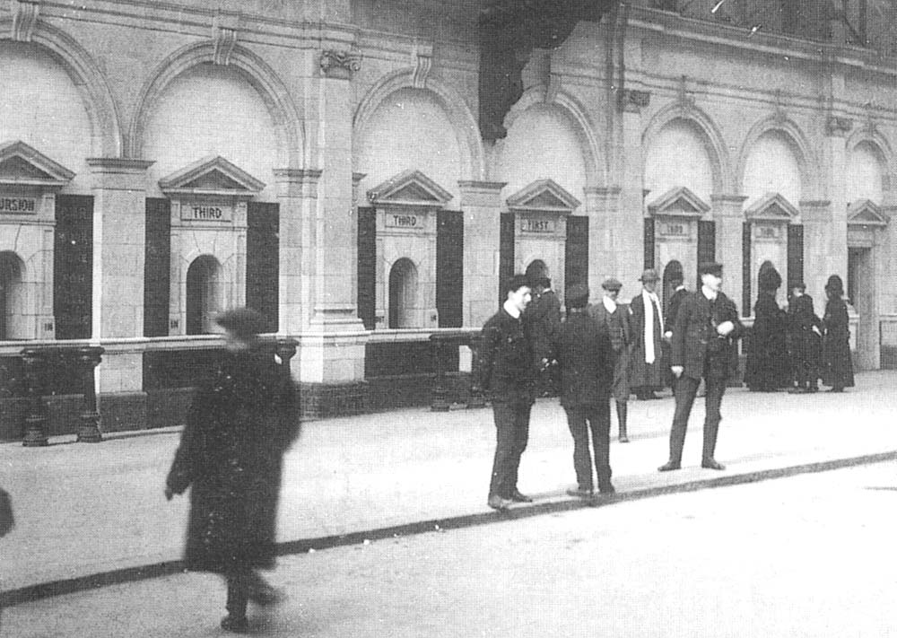 Close up within the Concourse area showing passengers queuing at the ticket offices whilst porters wait to help passengers