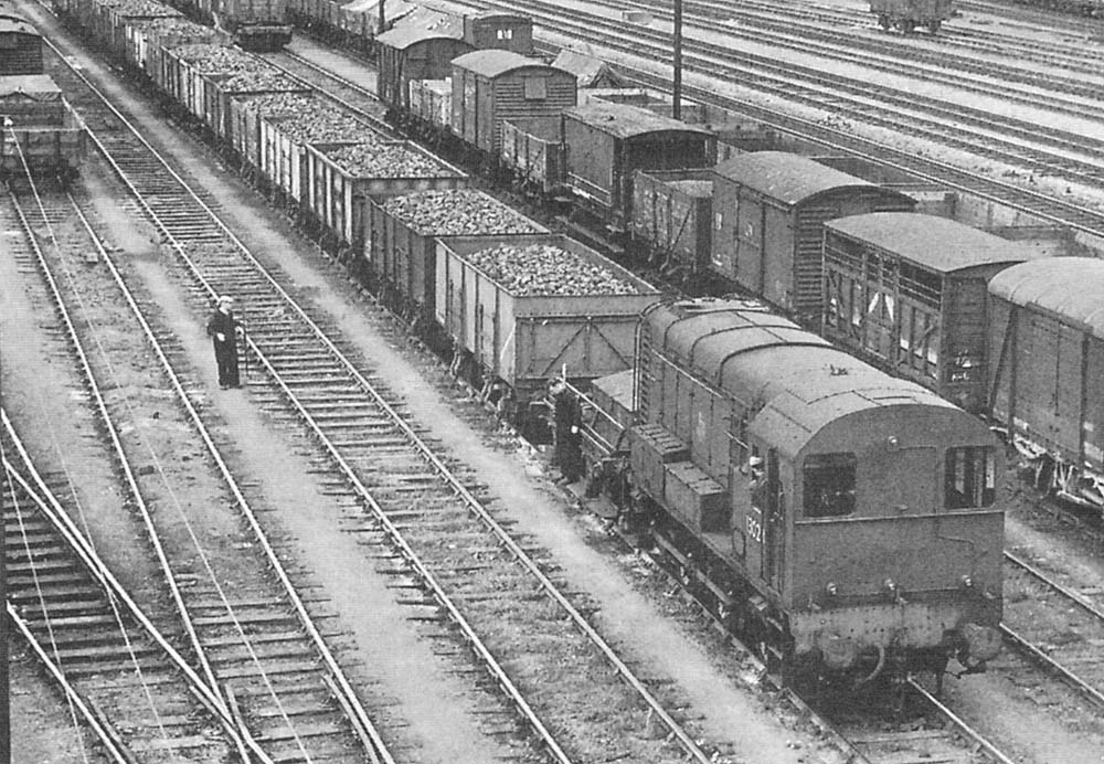 Close up showing a British Railways Class 08 Diesel at work with a GWR shunters truck attached in front and with two shunters in attendance