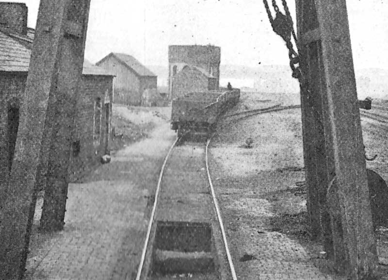Close up showing through the legs, and in the background, the shed's pump house and large circular water tank