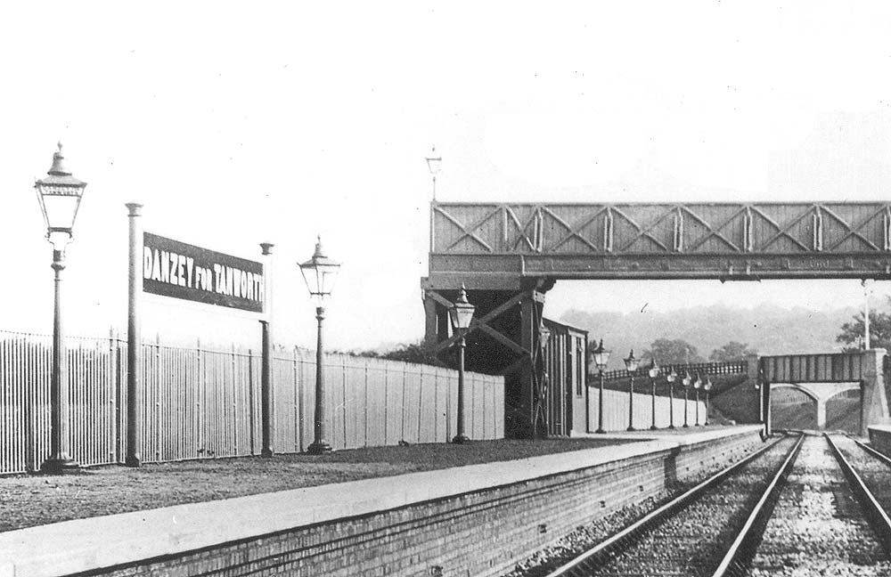 Close up showing the down platform and its simple passenger waiting room located at the bottom of the steps from the passenger footbridge