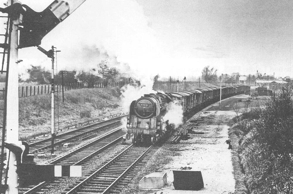 British Railways Standard Class 9F 2-10-0 No 92221, on a down Type 4 express freight working, has just past Earlswood Lakes station in early 1965