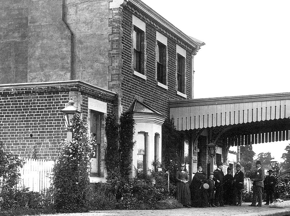 Close up of the station showing a group of villagers waiting for the arrival of the next train