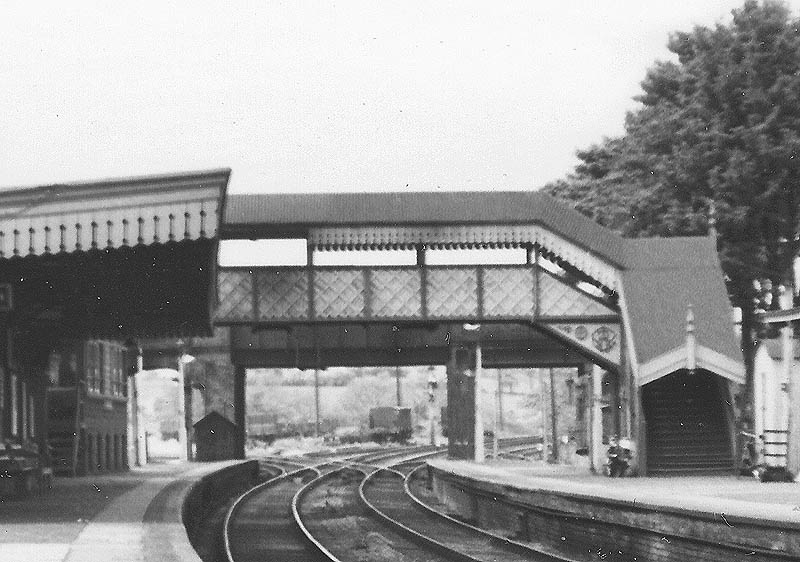 Close up showing the covered station footbridge and road bridge behind with Hatton Signal Box standing on the platform on the left