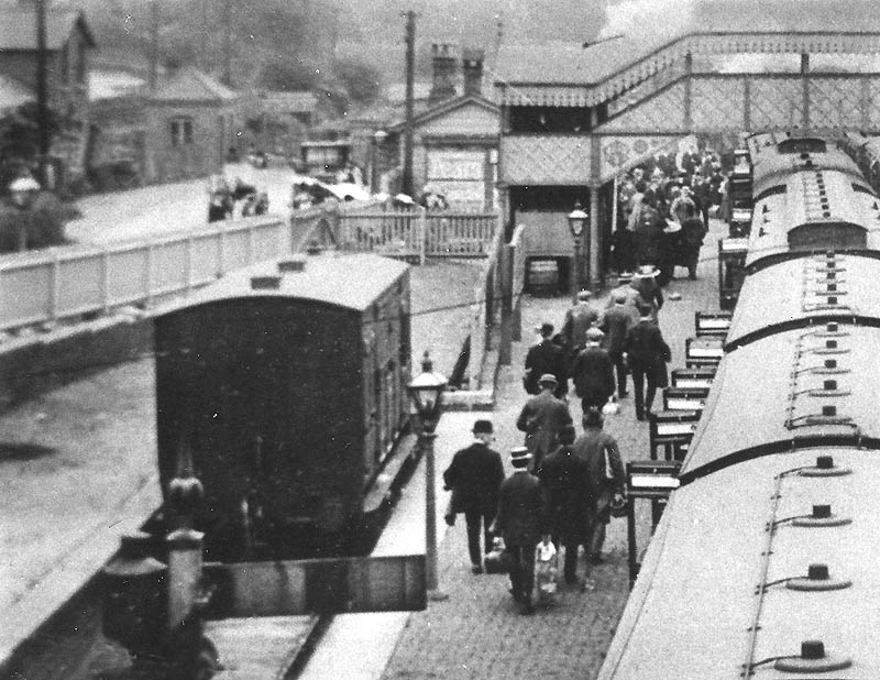 Close up of the main up platform, showing predominantly respectable male passengers alighting and the main station concourse