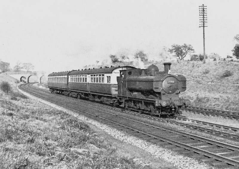 Ex-Great Western Railway 0-6-0T 57xx class No 7702 on the down main line with a Leamington to Stratford-upon-Avon local on 6th May 1953