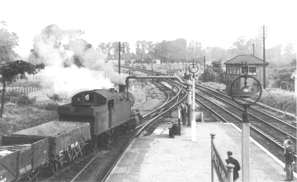 An unidentified ex-GWR 2-8-2T 72xx class locomotive is seen taking on water while held on the up bay loop line waiting its turn to proceed with a northbound freight circa 1950