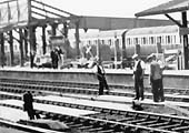 Close up showing workmen laying timber planking to the track and track bed between the up and down platforms