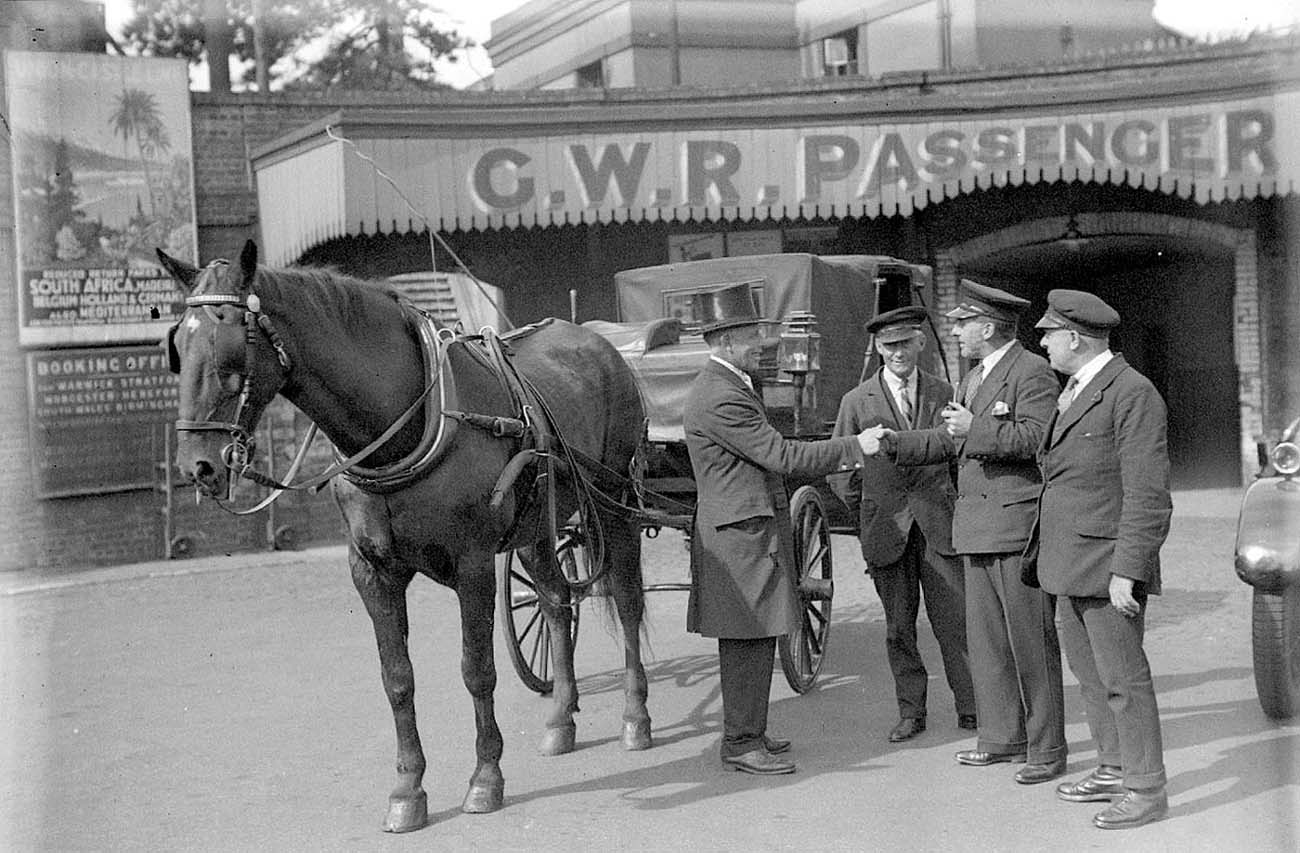 Horse drawn cab and motor taxi stand side by side outside the subway prior to the rebuilding