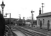 A GWR' 1076' class 0-6-0ST is seen at the head of a short goods train standing adjacent to the water column