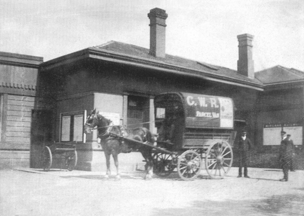 View showing the parcels offices next to the main station building and a parcels van together with a luggage cart