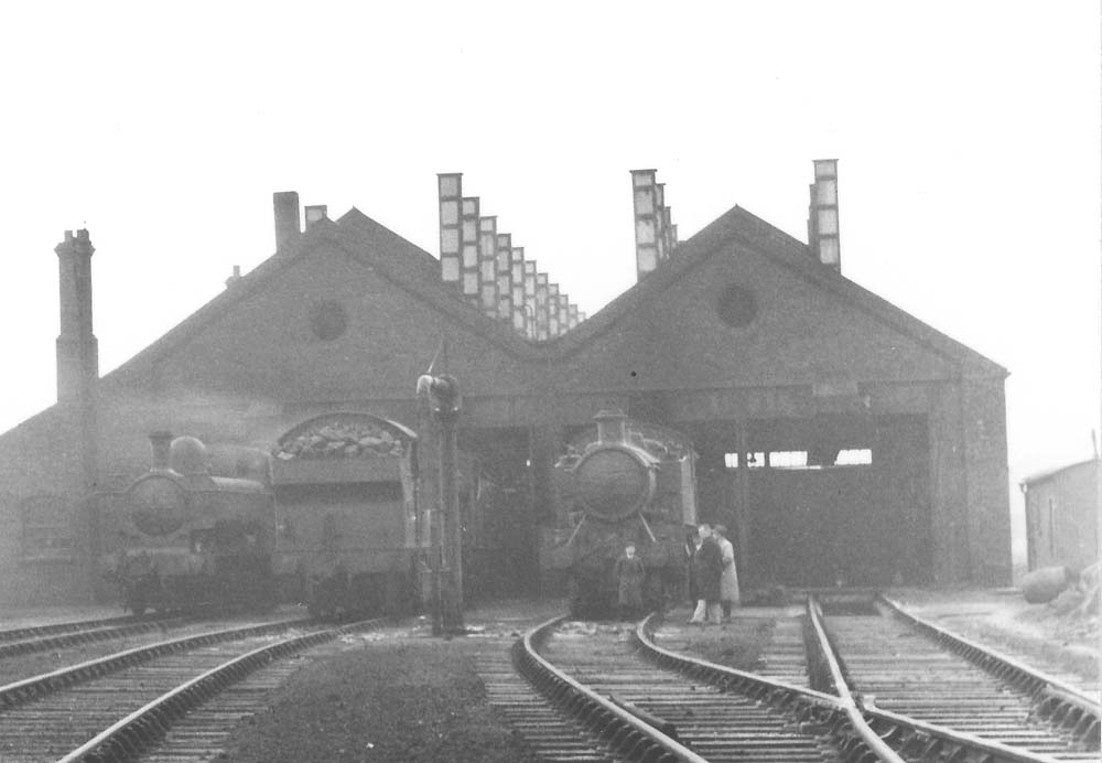 Close up showing enthusiasts standing next to the locomotives stabled in front of the four road shed