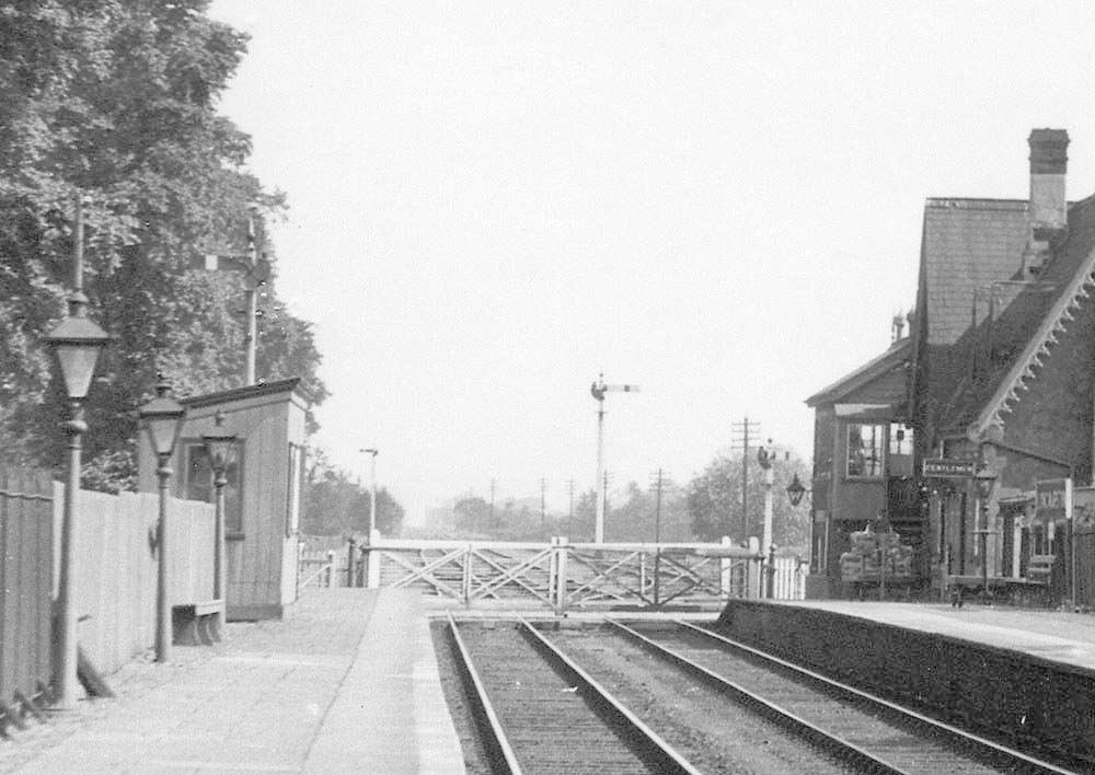 Close up showing the level crossing and the down refuge siding beyond the gates together with the waiting room built from vertical timber boarding