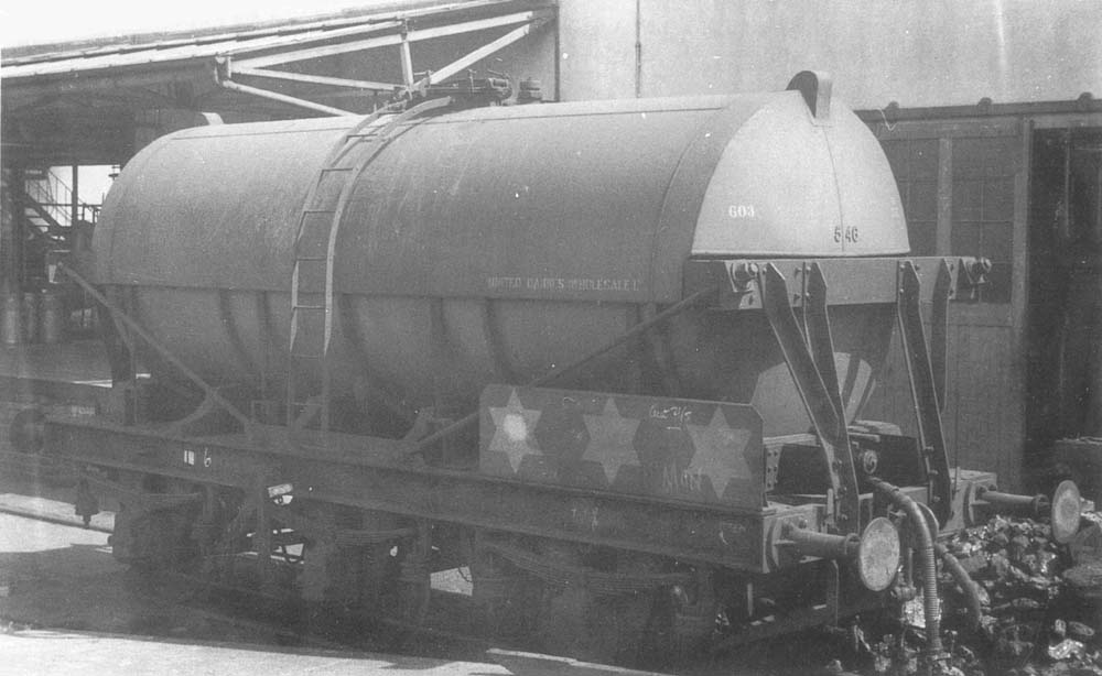 View of a six-wheel milk tank wagon standing in the siding alongside the Creamery with milk churns on the goods platform behind