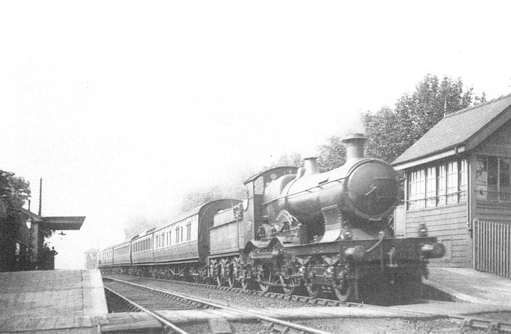 An unidentified GWR 4-4-0 Badminton class locomotive is seen at the head of an up express as it passes Olton station's redundant signal box
