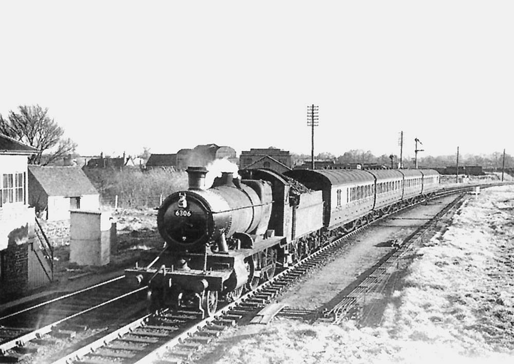 Ex-GWR 2-6-0 43xx class No 6306 is seen passing Stratford on Avon Junction Signal Box with a four-coach Worcester to Birmingham service