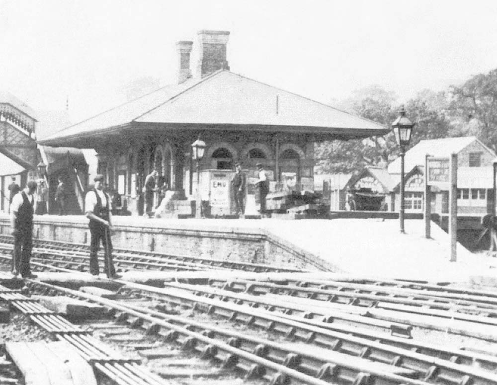 Close up showing Permanent Way workers working on a turnout next to the barrow crossing with the up platform in the background