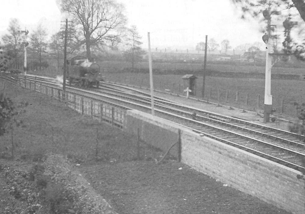 View of an unidentified GWR 2-4-2T 36xx class locomotive running light engine towards Stratford on Avon West Signal Box with the up refuge siding behind