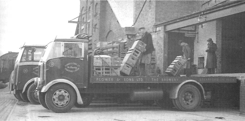 Lorries being loaded with bottled beer direct from the bottling plant's loading dock and of the barley house seen in the background