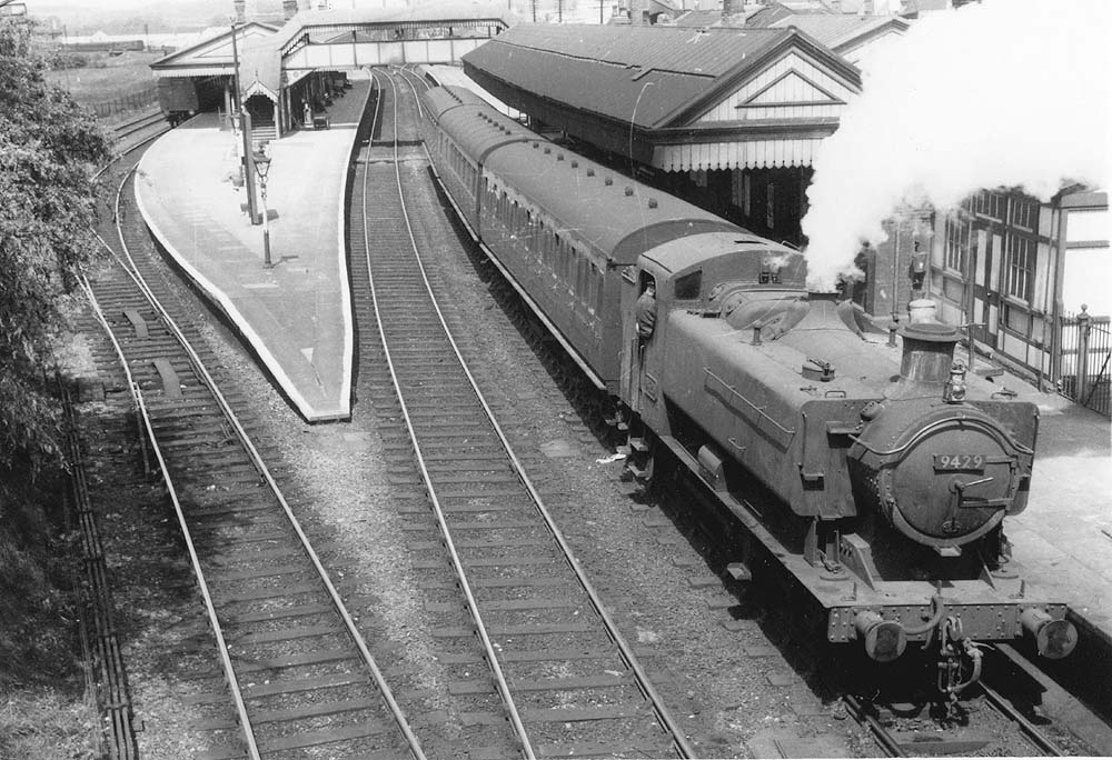 British Railways built 0-6-0PT 94xx class No 9429 is seen standing at the down platform on a three-coach local service to Honeybourne