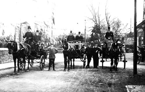 Looking towards Alcester Road along the main approach to Stratford on Avon station showing horse-drawn carriages posed outside