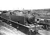 Close up showing a GWR 0-6-0 'Dean goods' locomotive standing on one of the approach roads in front of the sheds with the doors to the repair shops on the right
