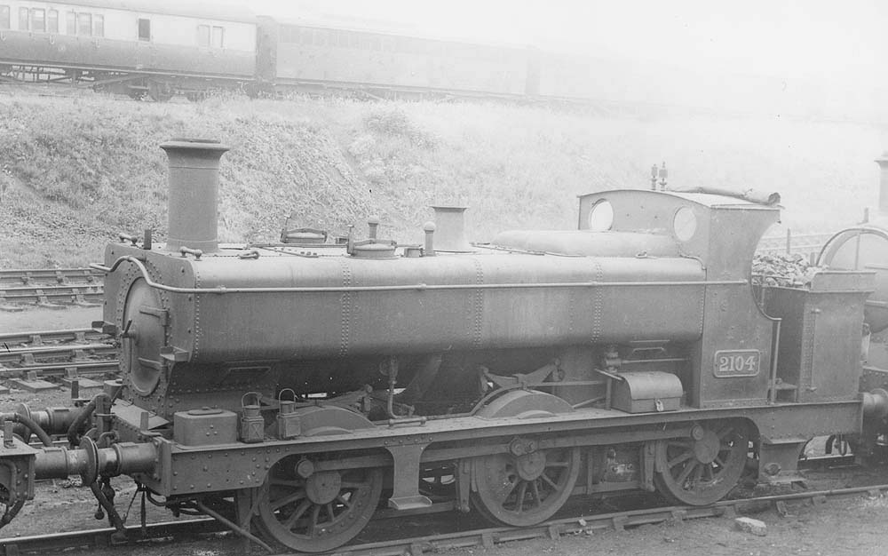 GWR 0-6-0PT No 2104, a half-cab class 2021 design, is standing near the carriage sidings in line with other locomotives