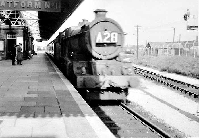 An unidentified ex-GWR 4-6-0 King class locomotive is seen passing Tyseley station's up main platform at the head of a Birkenhead to Paddington express