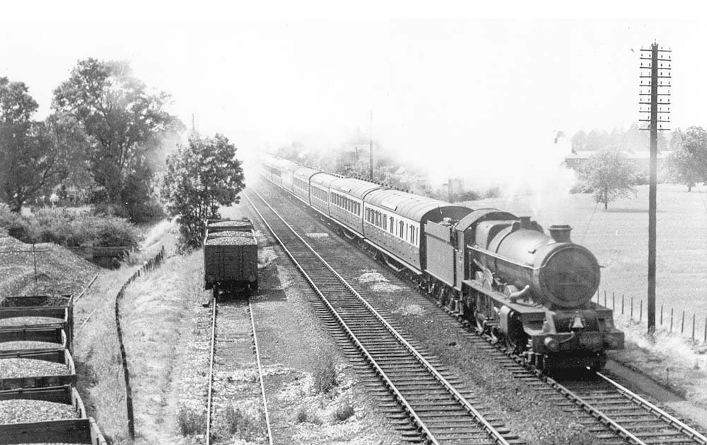 GWR 4-6-0 No 6000 'King George V' the pioneer of this class of locomotives hurries past Warwick Corporation's gas work sidings with an up express