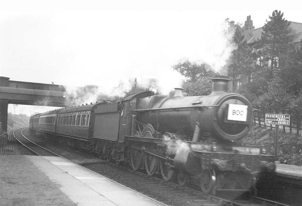 GWR 4-6-0 Hall class No 5930 'Hanngton Hall' is seen passing through the station at speed whilst at the head of a down West Country excursion train