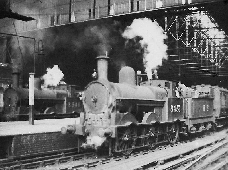 Ex-LNWR 0-6-0 18in Goods Engine No 8451 and sister engine No 8548 are both seen standing at the West end of New Street station at the head of local passenger services