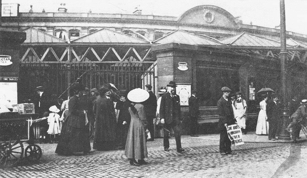Passengers mill around the locked gates of Station Street during the 1911 railway strike