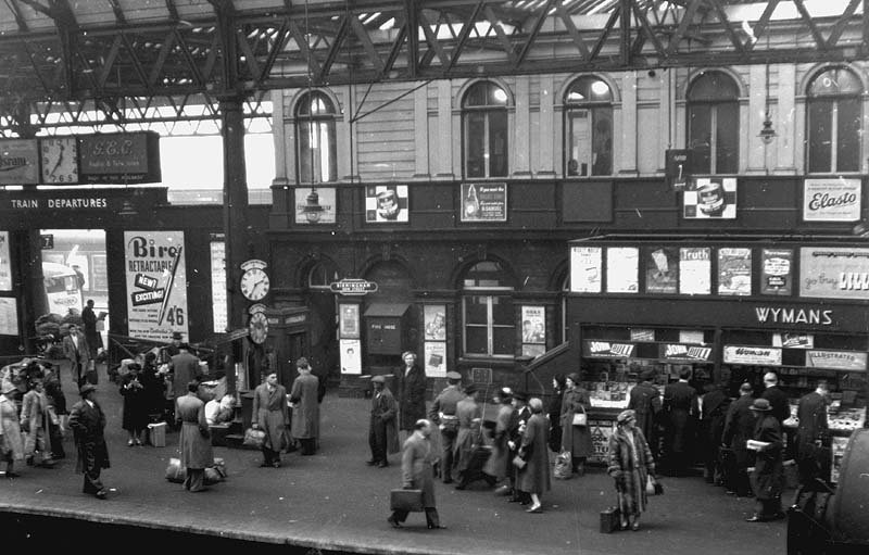 View of a very busy Platform 7 seen from the passenger footbridge looking towards Queens Drive showing the building which initially housed offices for Midland Railway staff